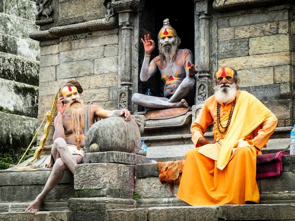 Three Indian saints sitting outside a temple